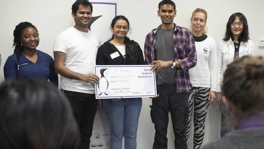 A group of participants in the hackaton holding a big check